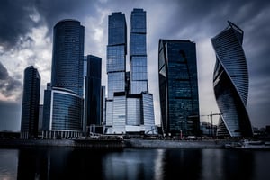 low-angle-shot-grey-skyscrapers-front-river-dark-cloudy-sky