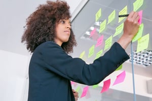 successful-pretty-businesswoman-writing-sticker-with-marker-thoughtful-confident-curly-female-manager-sharing-idea-project-making-note-brainstorming-business-training-concept